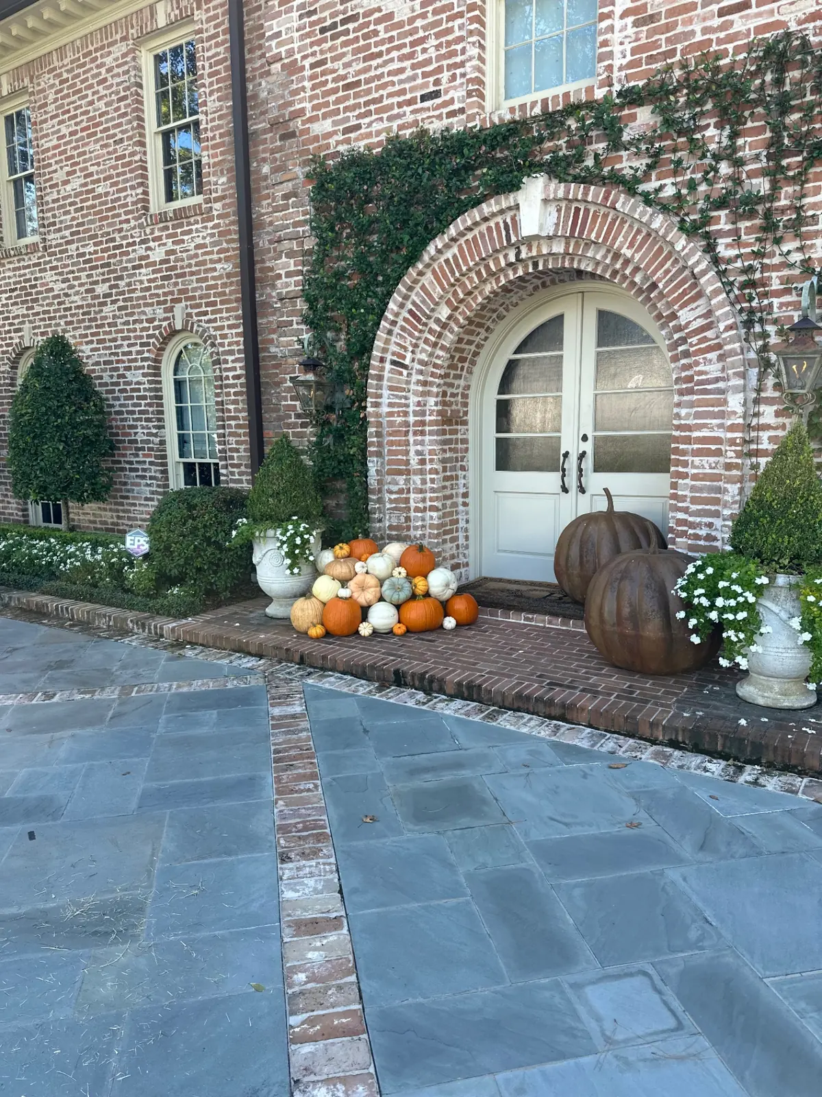 Arched brick entry with a stacked pile of heirloom pumpkins beside the doors, styled by West Pumpkin Bros